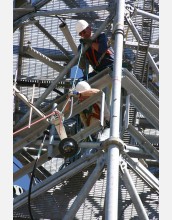 two men working in a communications tower lowering equipment with ropes