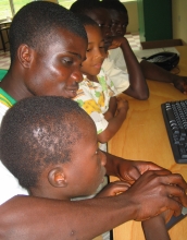 Older student helps younger student at the Ghana fab lab.