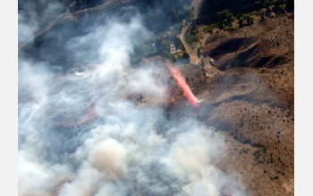 aerial view of wildfire with smaller plan below dispensing substance over flames