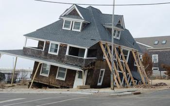 House sinking into sand by a coast