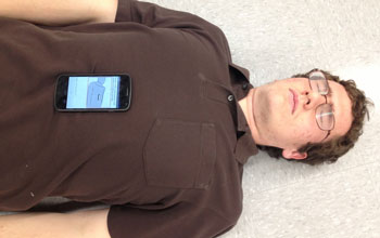 A smart phone placed on a man's chest to monitor breathing