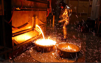 Workers remove molten iron from a pilot scale facility at Boston Metal in Woburn, Massachusetts