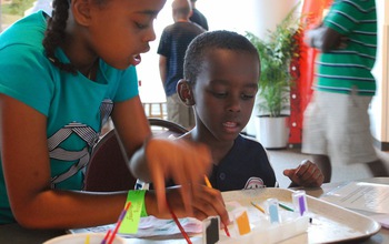 Young museum visitors use a paint set of acids and bases to learn about pH.