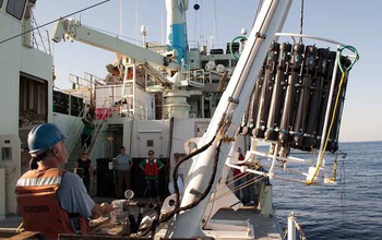 Scientists on ship lower instruments to collected water samples from the ocean.