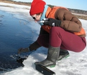 Woman sampling the overlying water of a frozen wetland in Acadia National Park.