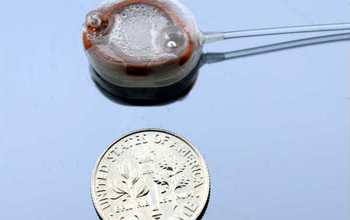 implantable infusion micropump next to a dime for size comparison