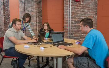 Professor Mihaela Sabin  with students at a table