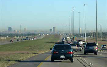 Photo of cars on a highway with smog in the distance.