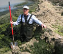 Researcher With shovel knee deep in an algae accumulation along Lake Erie