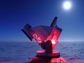 Photo of the South Pole Telescope illuminated by red lights.