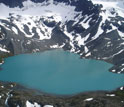 Photo of sharp-crested ridges of glacial debris that descend into Upper Greyling lake in Alaska.