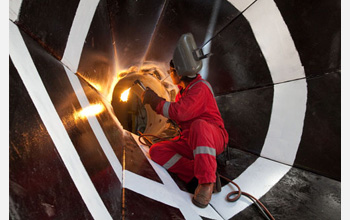 Photo of a welder working on a reentry cone used to guide drill pipe into the ocean floor.