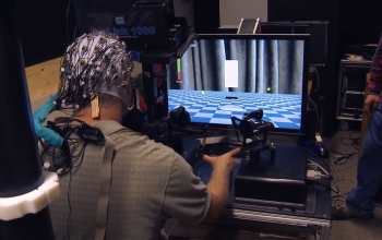 man with brain scan helmet using a computer