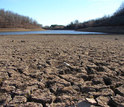 cracked soil near a river in an area affected by drought