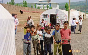 Children stand outside their makeshift classroom in the post-earthquake military tent city.