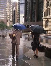 Photo of people holding umbrellas during a rain fall in a city.