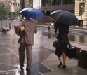 Photo of people holding umbrellas during a rain fall in a city.