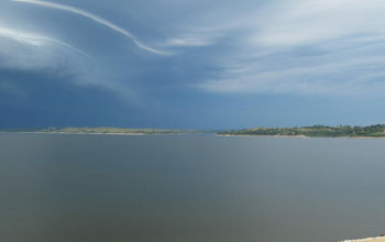 Photo of a body of water with a beach in the foreground and a finger of land in the center.