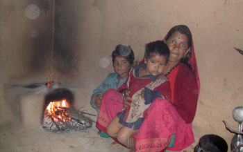 a Indian woman and her two children with a dung or wood fuel cooking stove.