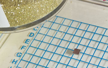 Photo of a square pad on a grid with a dish containing diamonds on the left.
