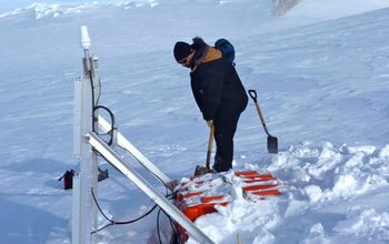 researcher digging out a seismographic instrument in Antarctica