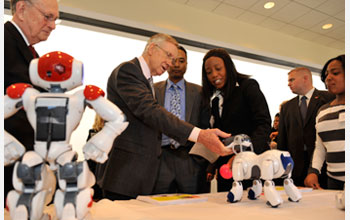 Photo of Sen. Reid interacting with soccer robot dogs.