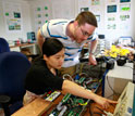 two students with technology for improving the electricity transmission system.