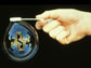 Image of a hand generating a bubble containing an image of the Exploratorium.
