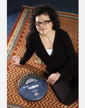 woman seated on rug next to blue, circular device labeled Roomba