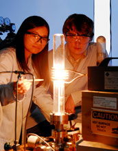Photo of students observing a high-temperature furnace used to produce graphene on a silicon wafer.