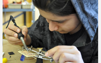 Photo of a student soldering together a solar powered robot.