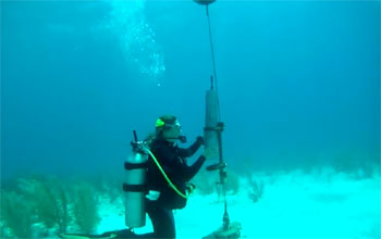 researcher under water holding a recording device.