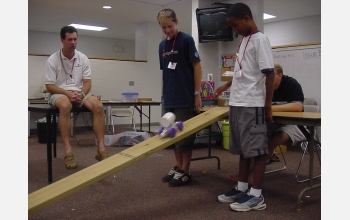 Students watch as robot rolls down plank.