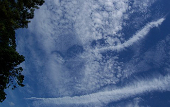 Hole-punch clouds appear over Norfolk, Va., with aircraft contrails leading from them.