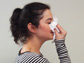 Photo of a woman blowing her nose into tissue.