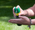 woman spraying insect repellant on hands