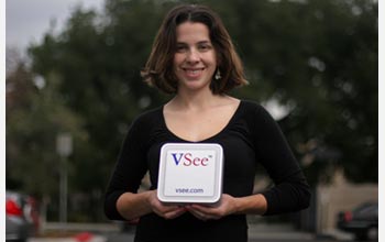 Photo of Colleen Beeson of VSee holding the hardware component of their virtual office system.