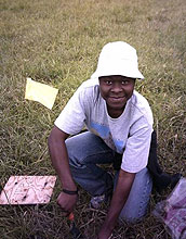 student kneels in field