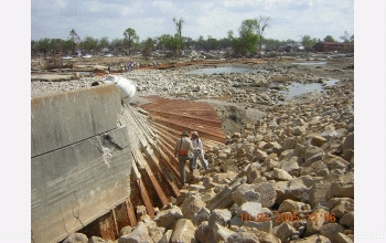 Researchers inspect a portion of the floodwall that was overtopped and flattened.