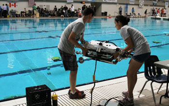 Team members standin next to a pool preparing to launch  their project
