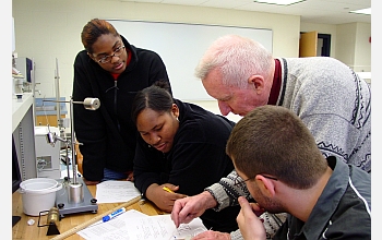 12th-grade physics students work with teacher.