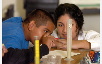 Teacher helps student with science experiment.