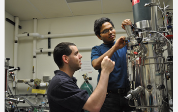 Photo of Ben Levinson watching Rama Balasubramanian adjust the levels of gases in a fermenter.