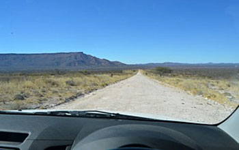 View through fron window of vehicle showing unpaved gravel road in Namibia.
