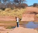 Photo of geologist Kyle Nichols standing next to wet river crossing in Namiba.