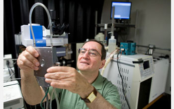 Photo of Professor Wachs examining an environmental reaction cell into which he places catalysts.