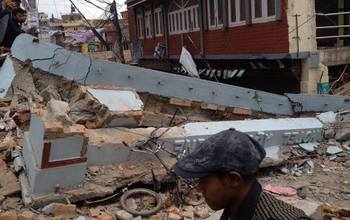 people next to rubble from a house damaged by earthquake