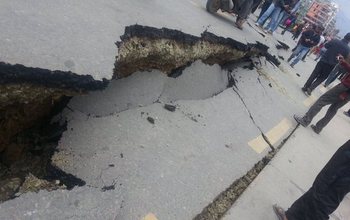 People standing next to road damaged by earthquake