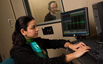 Photo of researcher and a colleague in a sound booth using a computer to record sound