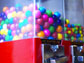 Photo of gumballs of different sizes in a gumball machine.